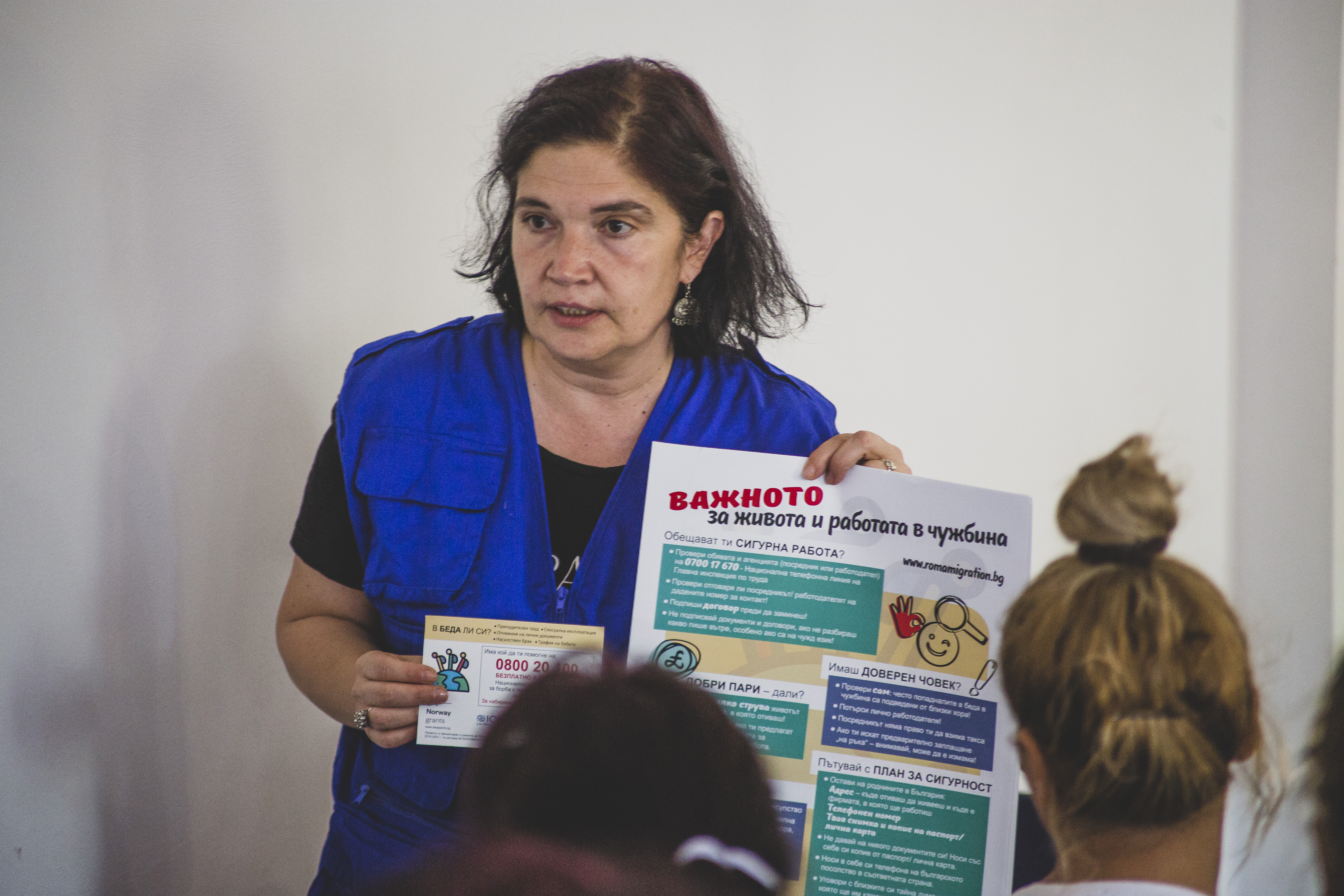 An IOM team member holding an info poster towards the audience