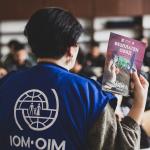 An IOM team member with an informational leaflet in front of an audience